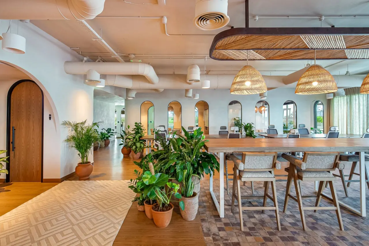 The Dubai office: an open-plan space with wooden tables, plants and arched doorways