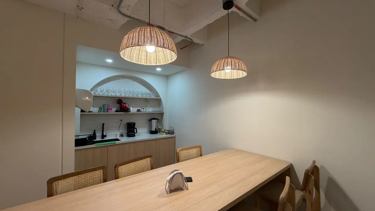 A meeting room with a wooden table and woven pendant lights in the Santiago office